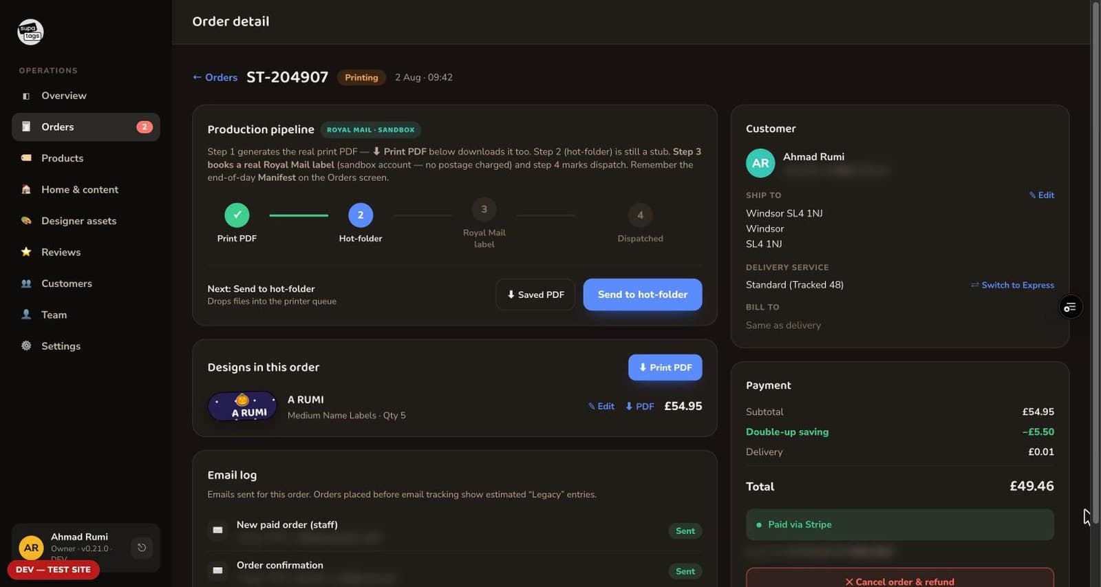One order open: a four-stage production pipeline from print file to hot-folder to Royal Mail label to dispatched, with the second stage current; the designs in the order; a log of the emails sent for it; and a payment panel showing the subtotal, a double-up saving, delivery and a Stripe capture. The customer email and the payment reference are blurred.